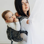 Woman holding a baby in a sling against a white background