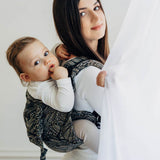 Woman holding a baby in a sling against a white background