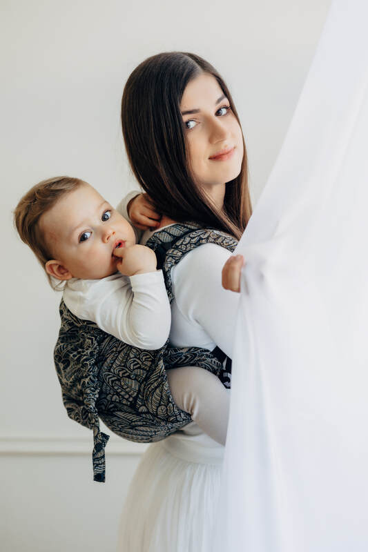 Woman holding a baby in a sling against a white background