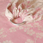 Close-up of a pink floral fabric with a metal ring on a matching pink background