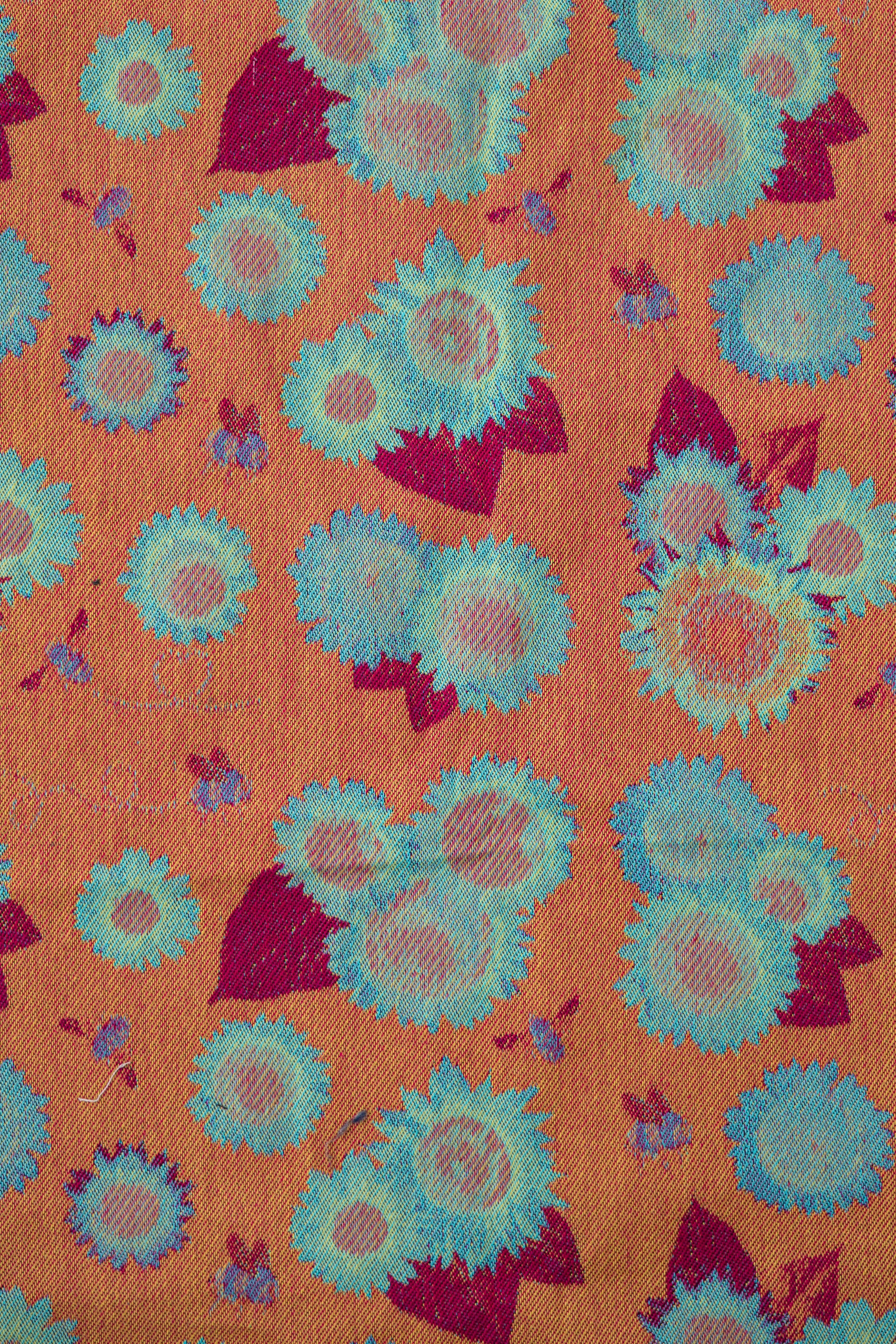 Decorative pattern with orange silhouettes of figures and foliage and skulls on a blue background