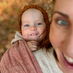 Prima Rosewood Woven Wrap by Didymos, baby smiling from a front carry outdoors